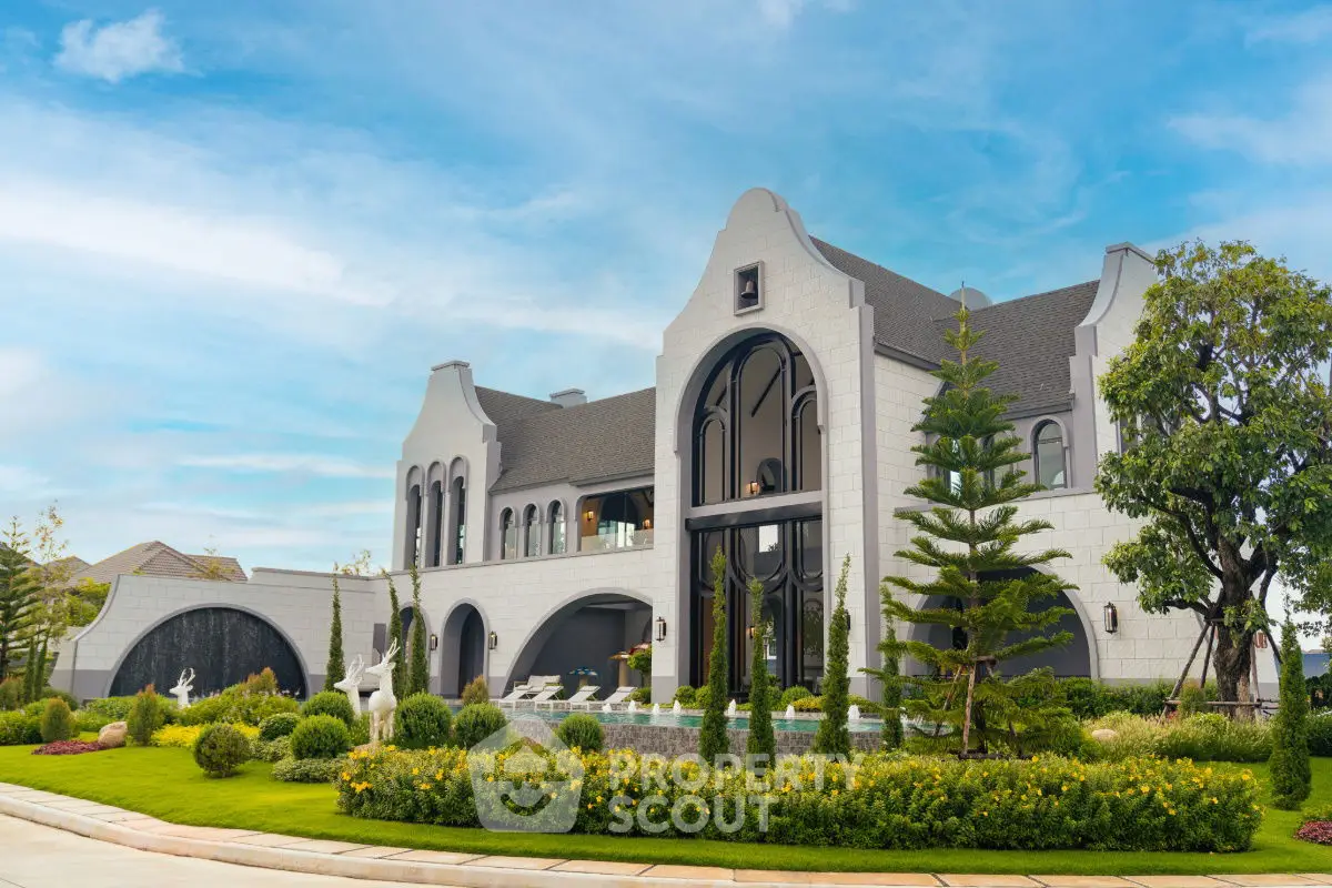 Luxurious mansion with unique architecture and lush garden under a clear blue sky.