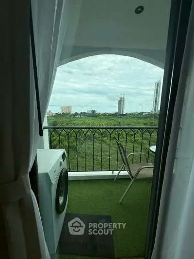 Charming balcony with lush green view and cozy seating area, perfect for relaxation.