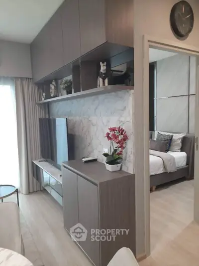 Modern living room with sleek TV unit and view into cozy bedroom
