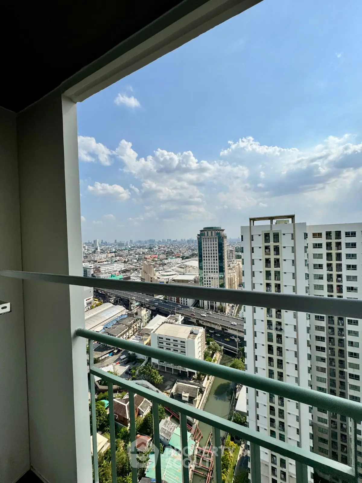 Stunning high-rise balcony view overlooking cityscape with clear blue skies, perfect for urban living.