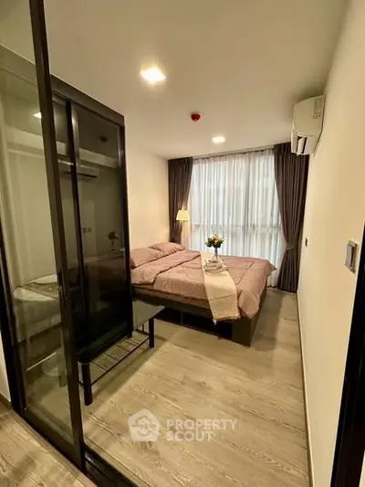 Modern bedroom with glass partition and cozy decor in a stylish apartment.