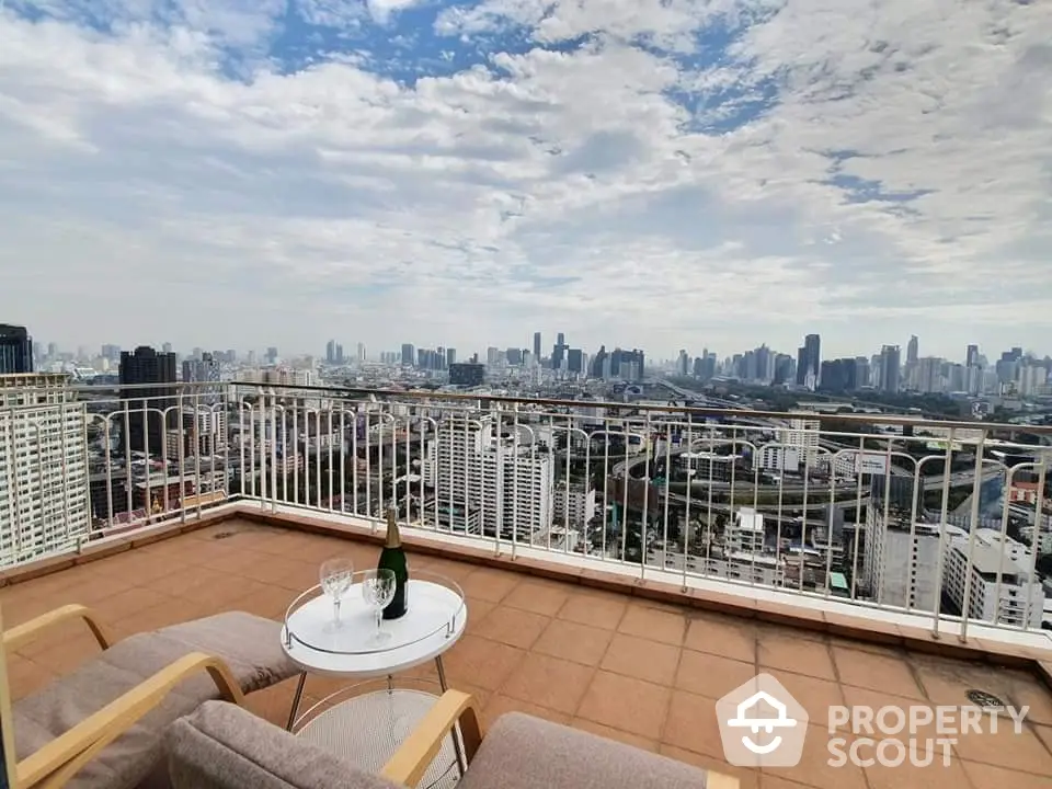 Stunning cityscape view from a spacious balcony with cozy seating and table.