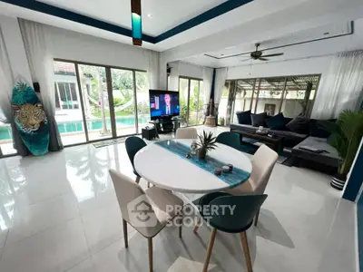 Spacious living room with pool view, modern decor, and elegant dining area in luxury home.