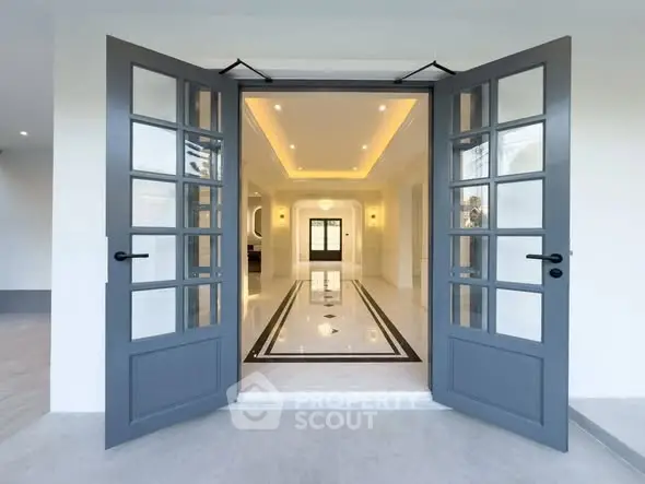 Elegant entrance with double doors leading to a luxurious interior hallway with stylish lighting.