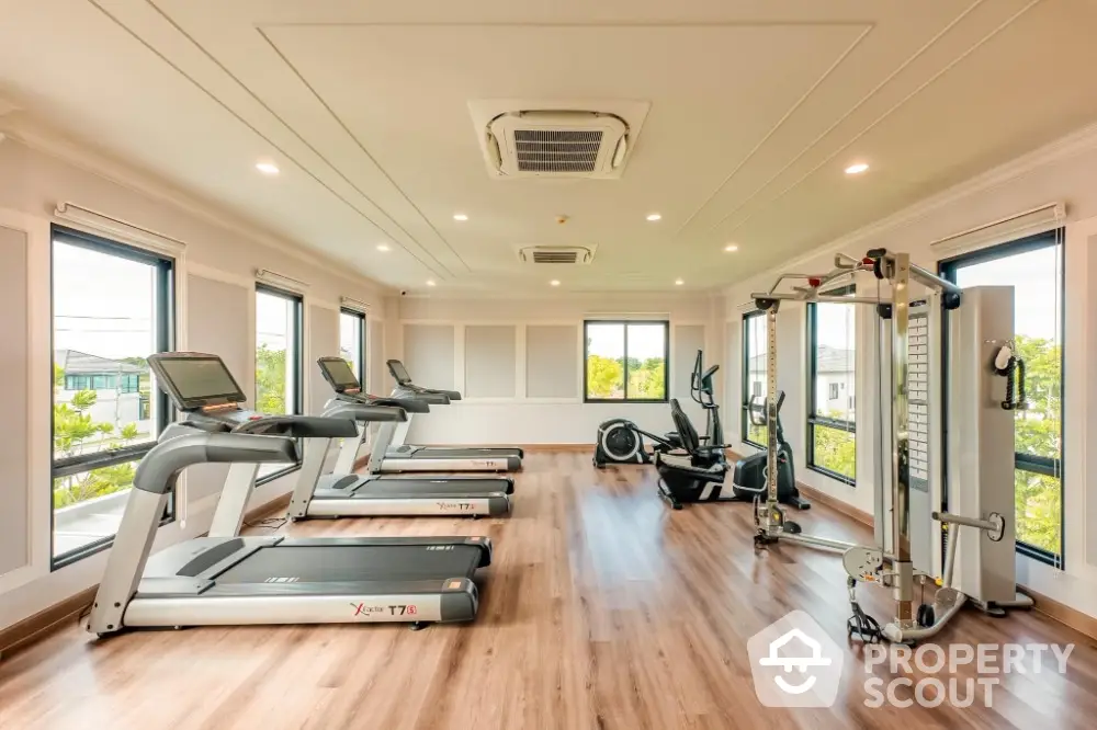 Spacious modern gym with state-of-the-art equipment and large windows offering scenic views.