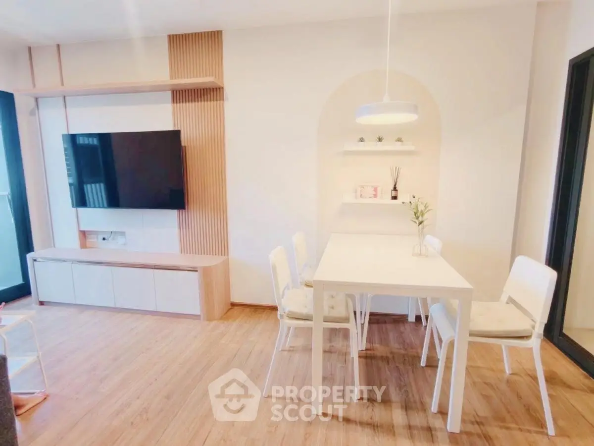 Modern dining area with sleek wooden flooring and wall-mounted TV, perfect for stylish living.