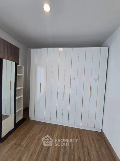 Spacious bedroom with modern wardrobe and wooden flooring