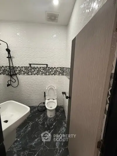 Modern bathroom with sleek black and white design, featuring a stylish sink and shower area.