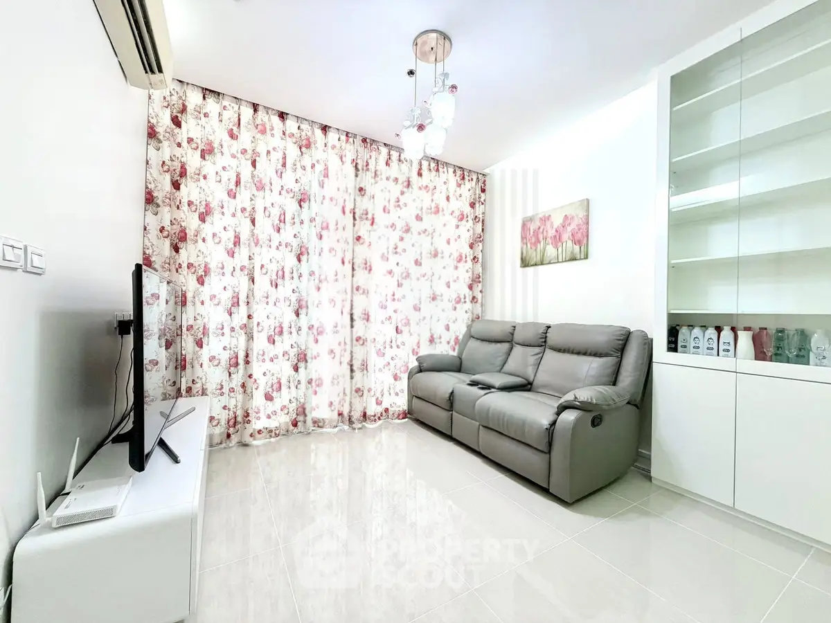 Modern living room with floral curtains, sleek sofa, and elegant lighting.