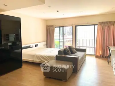 Spacious studio apartment with modern furnishings and large windows offering city views.