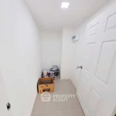 Compact storage room with white walls and tiled floor, ideal for organizing supplies.