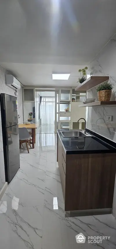 Modern kitchen with sleek design and dining area, featuring marble flooring and stylish cabinetry.