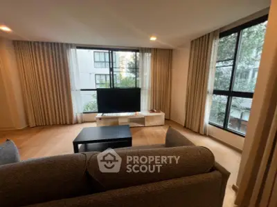 Spacious living room with large windows and modern decor in a stylish apartment.