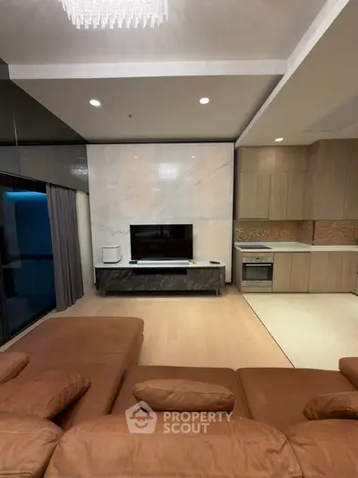 Luxurious modern living room with open kitchen, featuring sleek marble wall and stylish leather sofa.