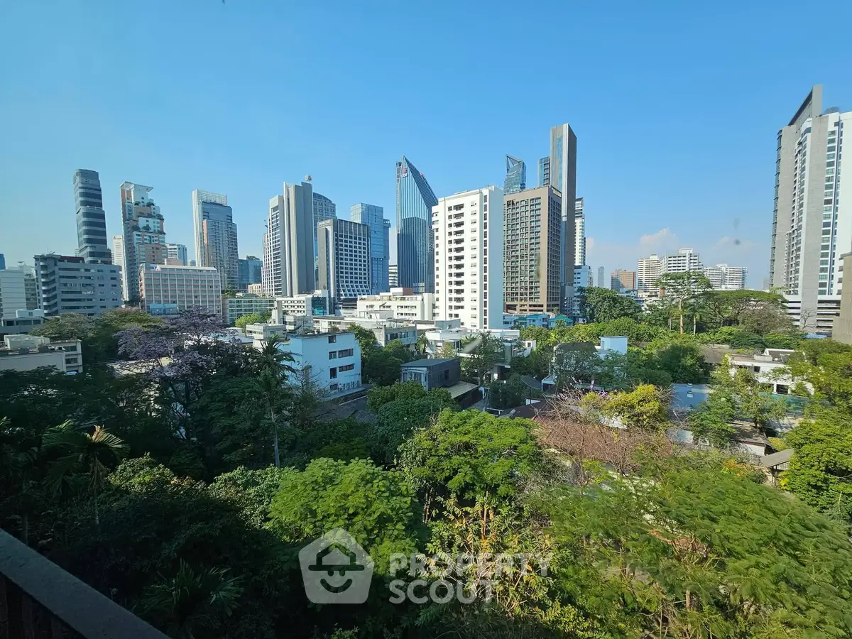 Stunning cityscape view with lush greenery and modern skyscrapers under a clear blue sky.