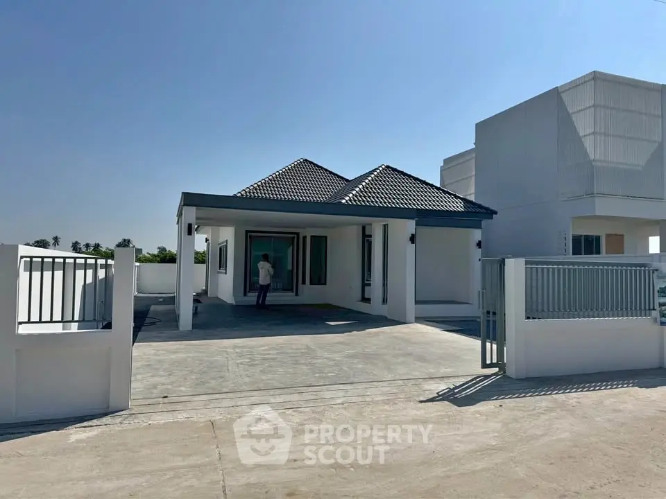 Modern single-story house with spacious driveway and contemporary design.