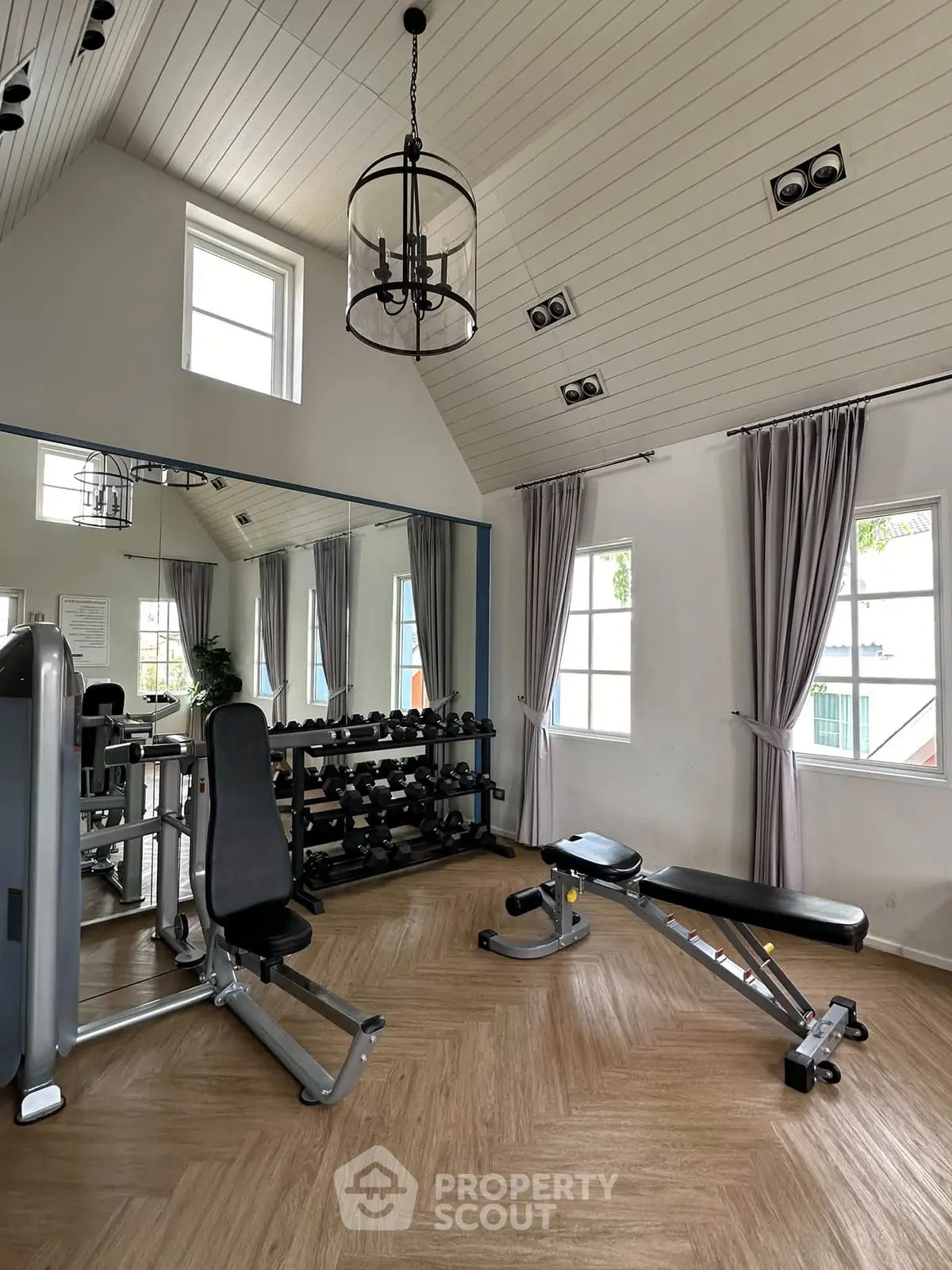 Modern gym with high ceilings, mirrored wall, and fitness equipment in a stylish residential building.
