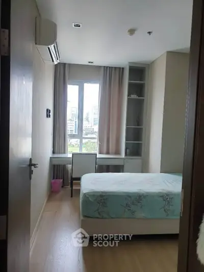 Cozy bedroom with city view, featuring a comfortable bed and study desk, perfect for urban living.