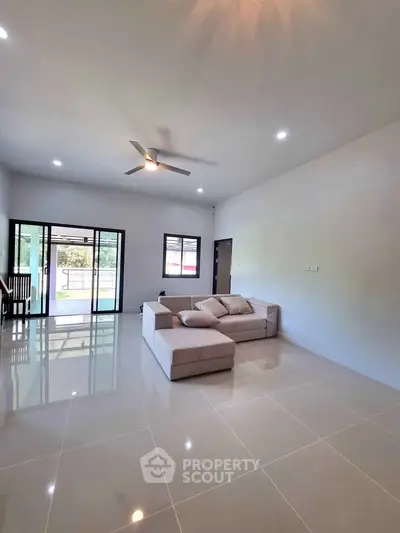 Spacious modern living room with sleek tile flooring and cozy sofa, featuring large windows for natural light.