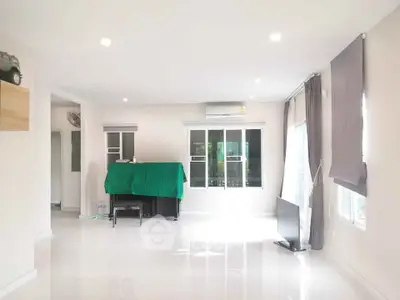Spacious living room with large windows and modern decor, perfect for natural light lovers.