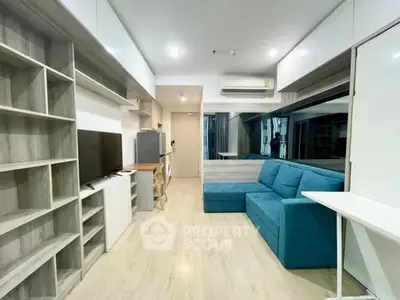 Modern living room with blue sofa, TV, and sleek storage solutions.