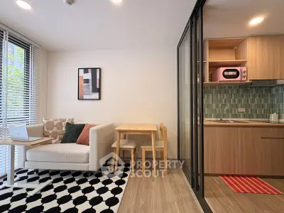 Modern living room with cozy seating and stylish kitchen in open layout apartment.