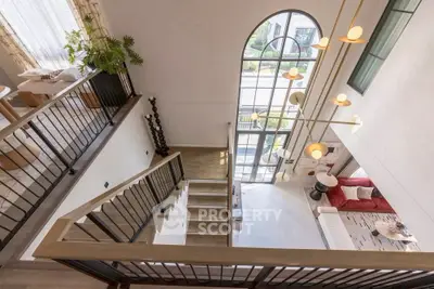 Stunning modern living room with high ceilings and large arched window, offering a bright and airy atmosphere.