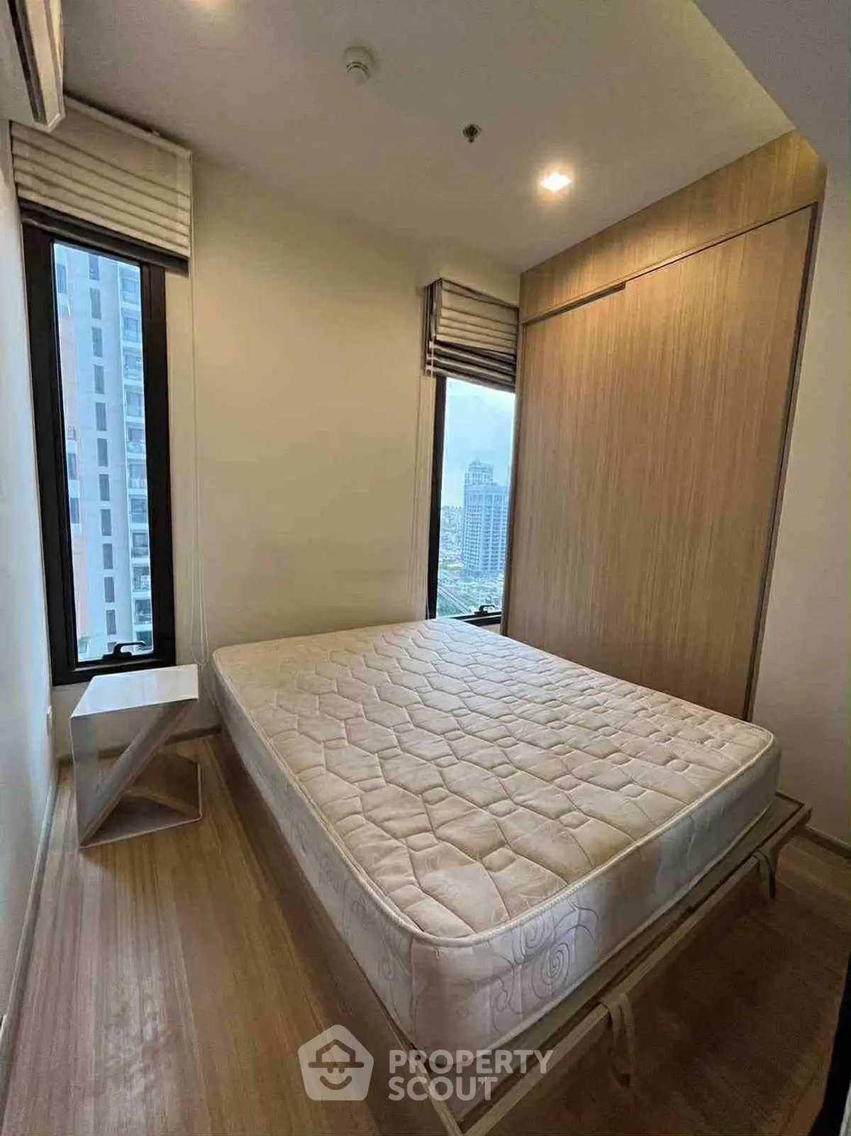 Cozy bedroom with large windows offering city views, featuring a comfortable bed and modern design.