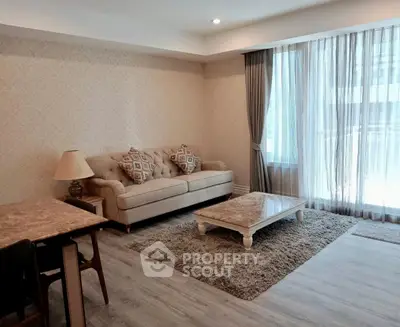 Elegant living room with plush sofa, stylish coffee table, and large window with sheer curtains.