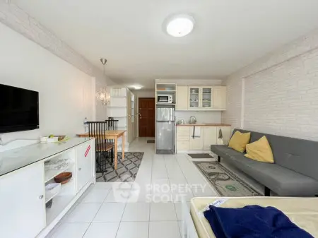 Modern open-plan living room with kitchen, featuring sleek furniture and bright decor.