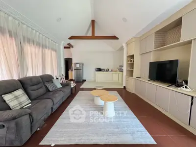 Spacious living room with modern decor and vaulted ceiling, featuring a cozy sofa and entertainment center.