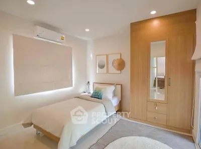 Cozy bedroom with modern decor, featuring a single bed, built-in wardrobe, and soft lighting.