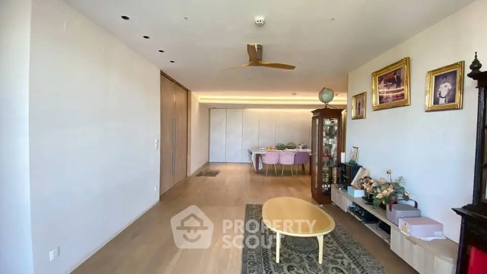 Spacious living room with elegant decor and dining area, featuring wooden flooring and modern lighting.