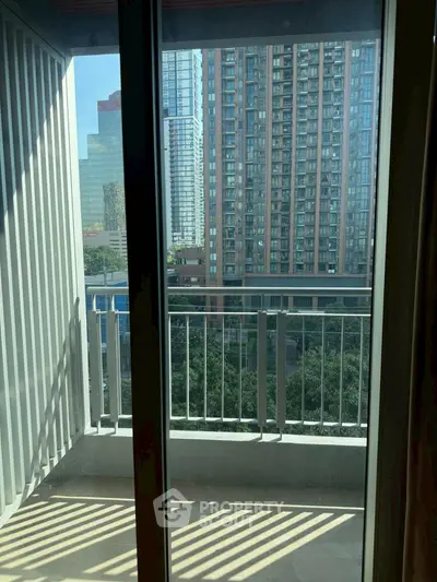 Modern high-rise balcony with cityscape view through glass doors.