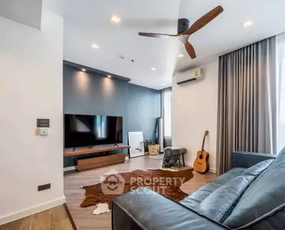 Modern living room with sleek design, featuring a TV, guitar, and stylish ceiling fan.