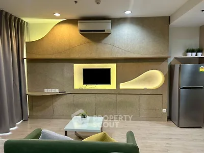 Modern living room with stylish wall design and mounted TV, featuring air conditioning and sleek furniture.