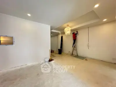 Spacious interior under renovation with modern lighting and worker on ladder