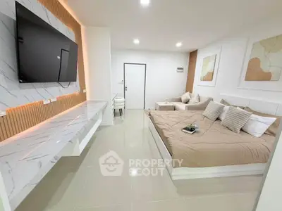 Modern living room with stylish decor and wall-mounted TV, featuring a cozy bed and elegant furnishings.