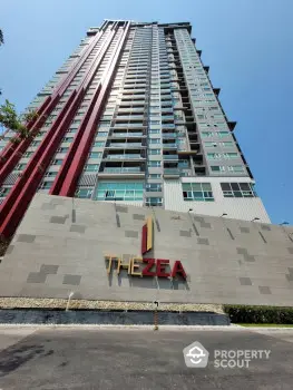 Modern high-rise building with sleek design and prominent signage under clear blue sky.