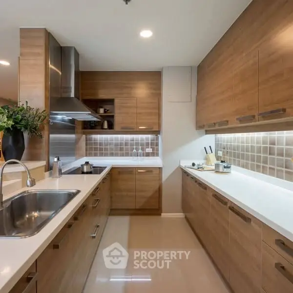 Modern kitchen with wooden cabinets and sleek countertops, featuring a stainless steel sink and stylish backsplash.