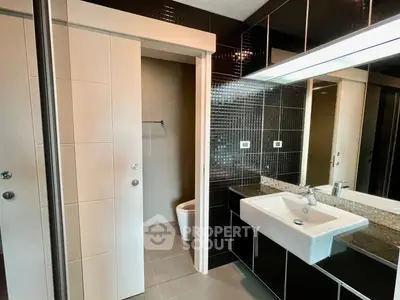 Modern bathroom with sleek black tiles and large mirror