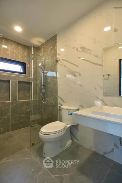 Modern bathroom with elegant marble tiles and glass shower enclosure.