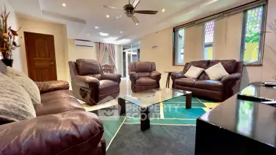 Spacious living room with leather sofas and modern decor, perfect for relaxation and entertainment.