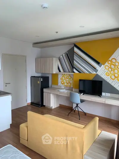 Modern living room with stylish decor and workspace, featuring a vibrant yellow sofa and sleek wooden flooring.
