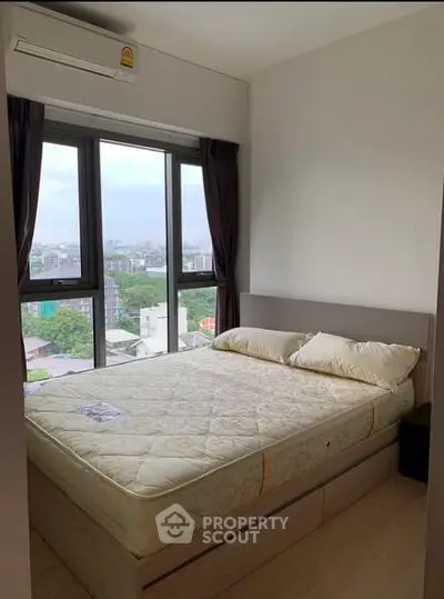 Cozy bedroom with large windows offering a stunning city view, perfect for urban living.