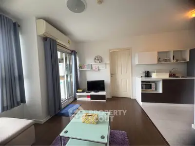Modern living room with open kitchen, featuring sleek furniture and natural light.