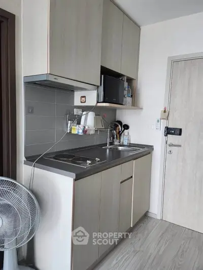 Modern compact kitchen with sleek cabinetry and stainless steel sink in a cozy apartment.