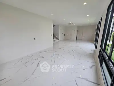 Spacious modern living room with marble flooring and large windows for natural light.