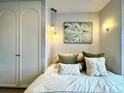 Cozy bedroom with stylish decor and soft lighting, featuring elegant wall art and plush pillows.