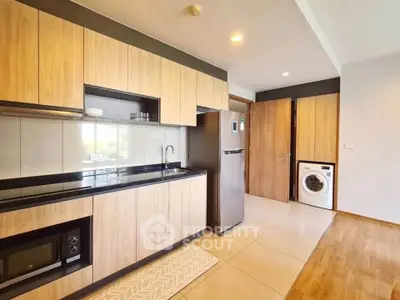 Modern kitchen with wooden cabinets, sleek appliances, and washing machine in stylish apartment.